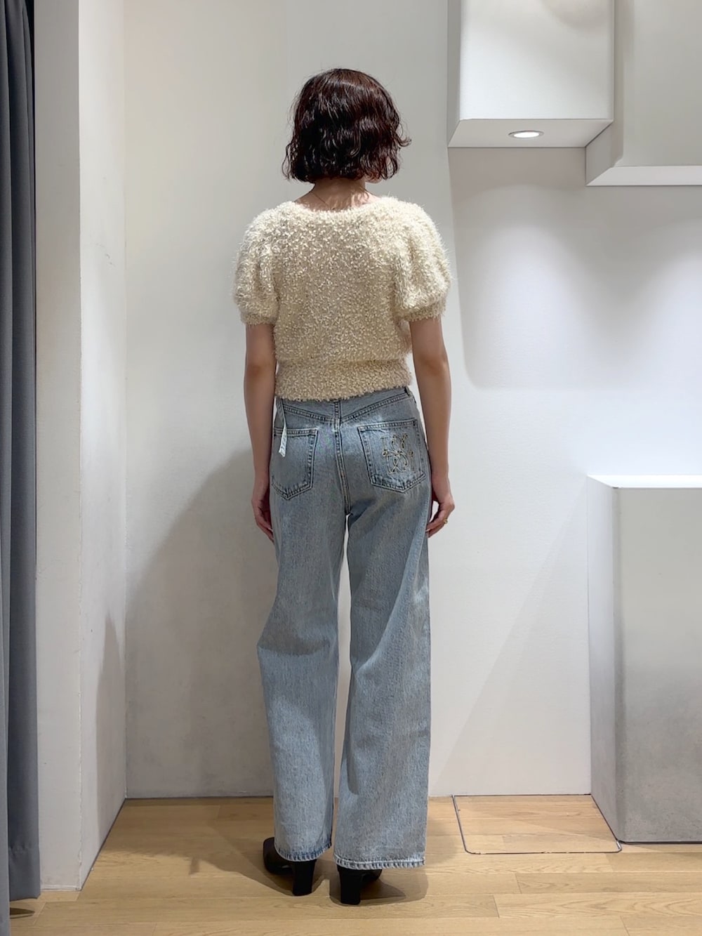 ホワイト系のニット/セーター、ブルー系のデニムパンツ、ブラック系のブーツを着用したレディースの秋コーディネートの9枚目の写真