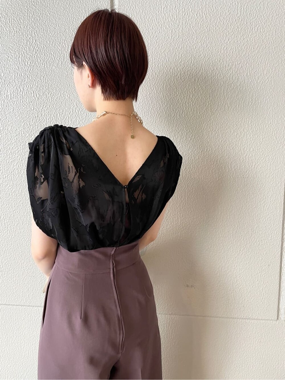 パープル系のパンツドレス、シルバー系のパンプス、ベージュ系のクラッチバッグを着用したレディースの春コーディネートの9枚目の写真