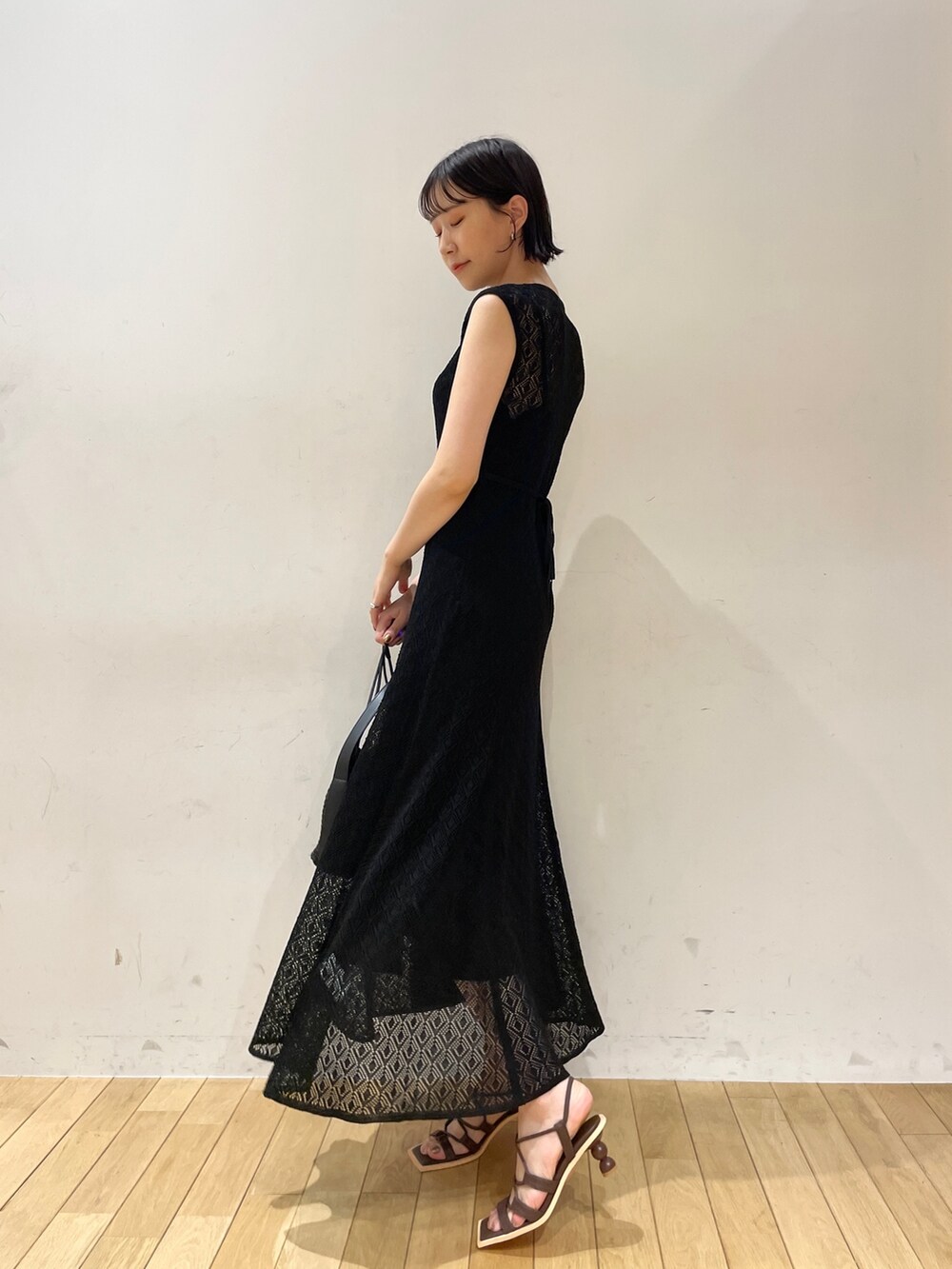 ブラック系のワンピース、ブラック系のハンドバッグ、ブラウン系のサンダルを着用したレディースの夏コーディネートの3枚目の写真