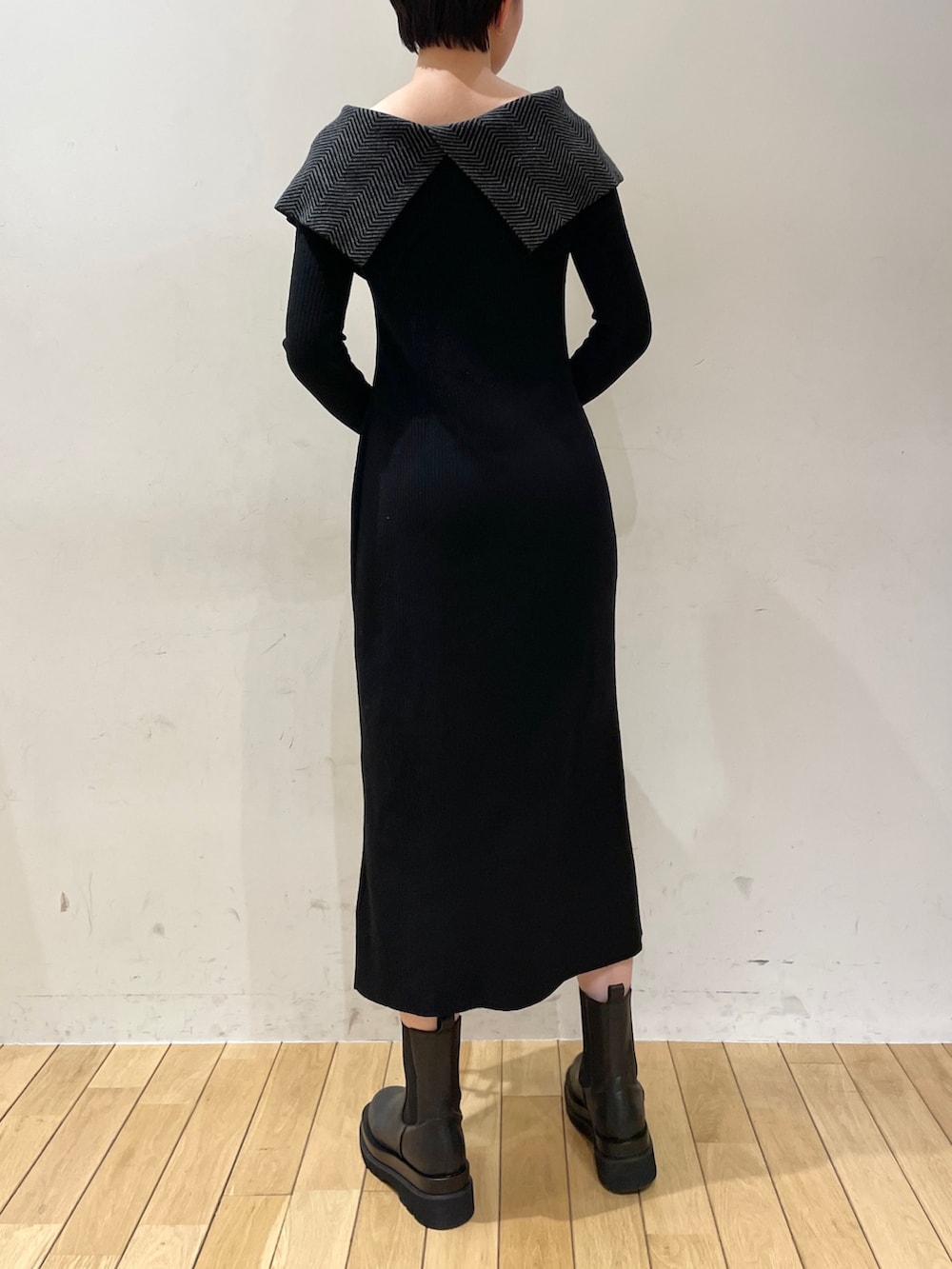 ブラック系のワンピース、ホワイト系のハンドバッグ、ブラック系のブーツを着用したレディースの冬コーディネートの4枚目の写真