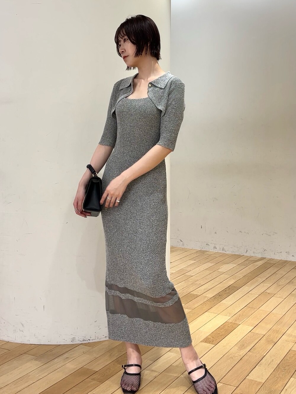 グレー系のワンピース、ブラック系のブルゾン、ブラック系のハンドバッグを着用したレディースの春コーディネートの6枚目の写真