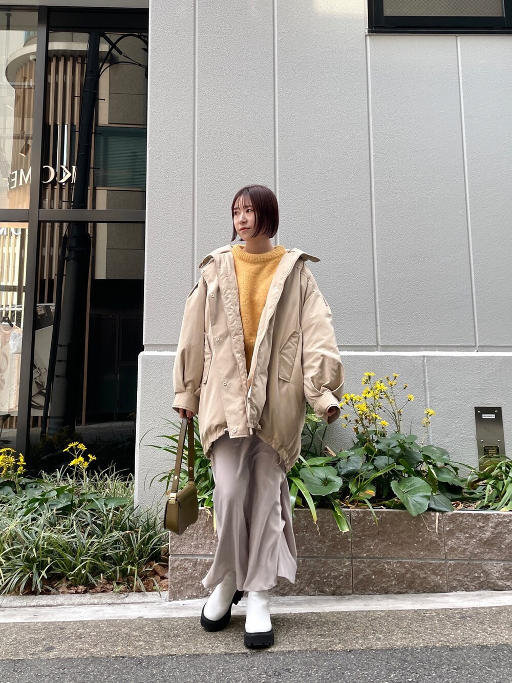 ベージュ系のダウンジャケット/コート、ホワイト系のスカート、ブラウン系のショルダーバッグを着用したレディースの冬コーディネートの2枚目の写真