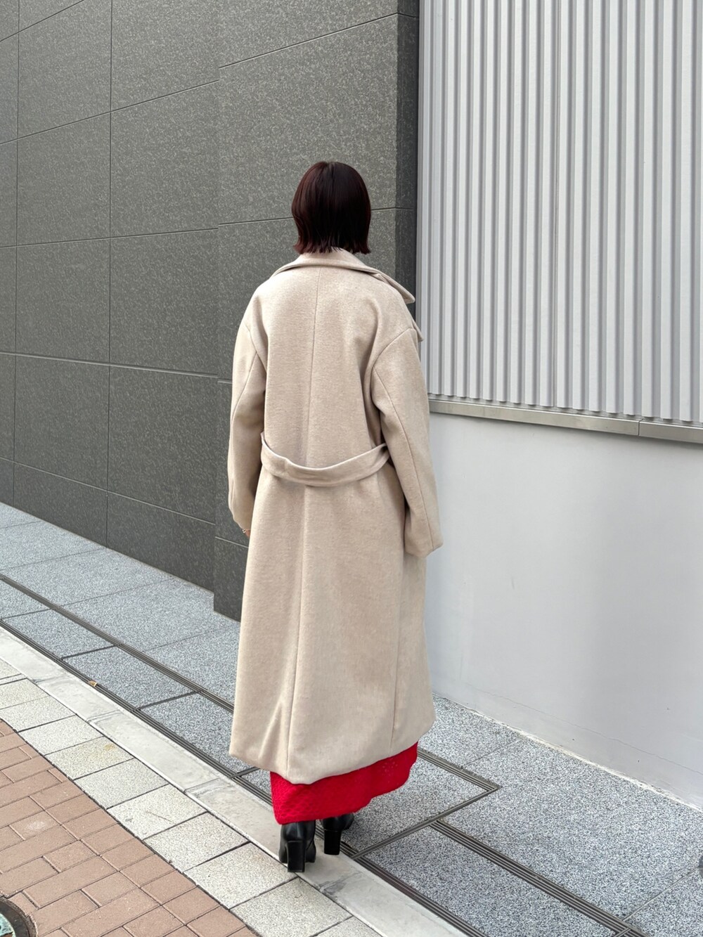 レッド系のワンピース、ホワイト系のチェスターコートを着用したレディースの冬コーディネートの4枚目の写真