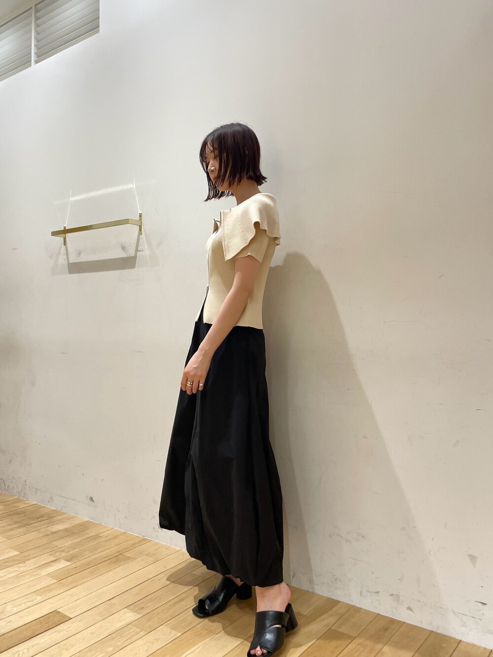 ブラック系のサンダル、ホワイト系のニット/セーター、ブラック系のスカートを着用したレディースの夏コーディネートの3枚目の写真