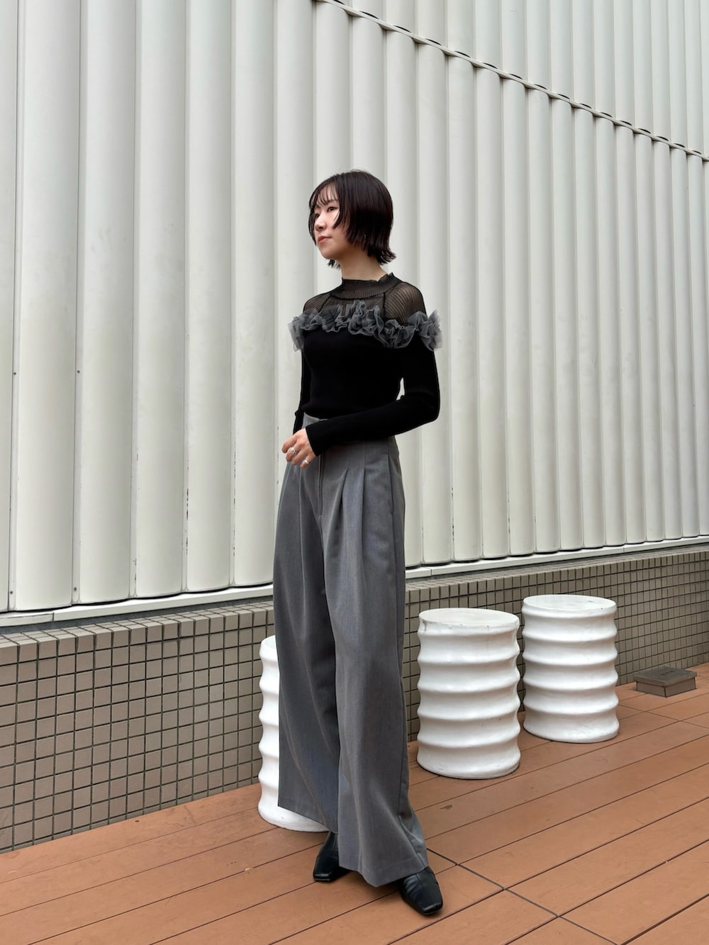 グレー系のその他パンツ、ブラック系のニット/セーター、ブラック系のブーツを着用したレディースの秋コーディネートの2枚目の写真