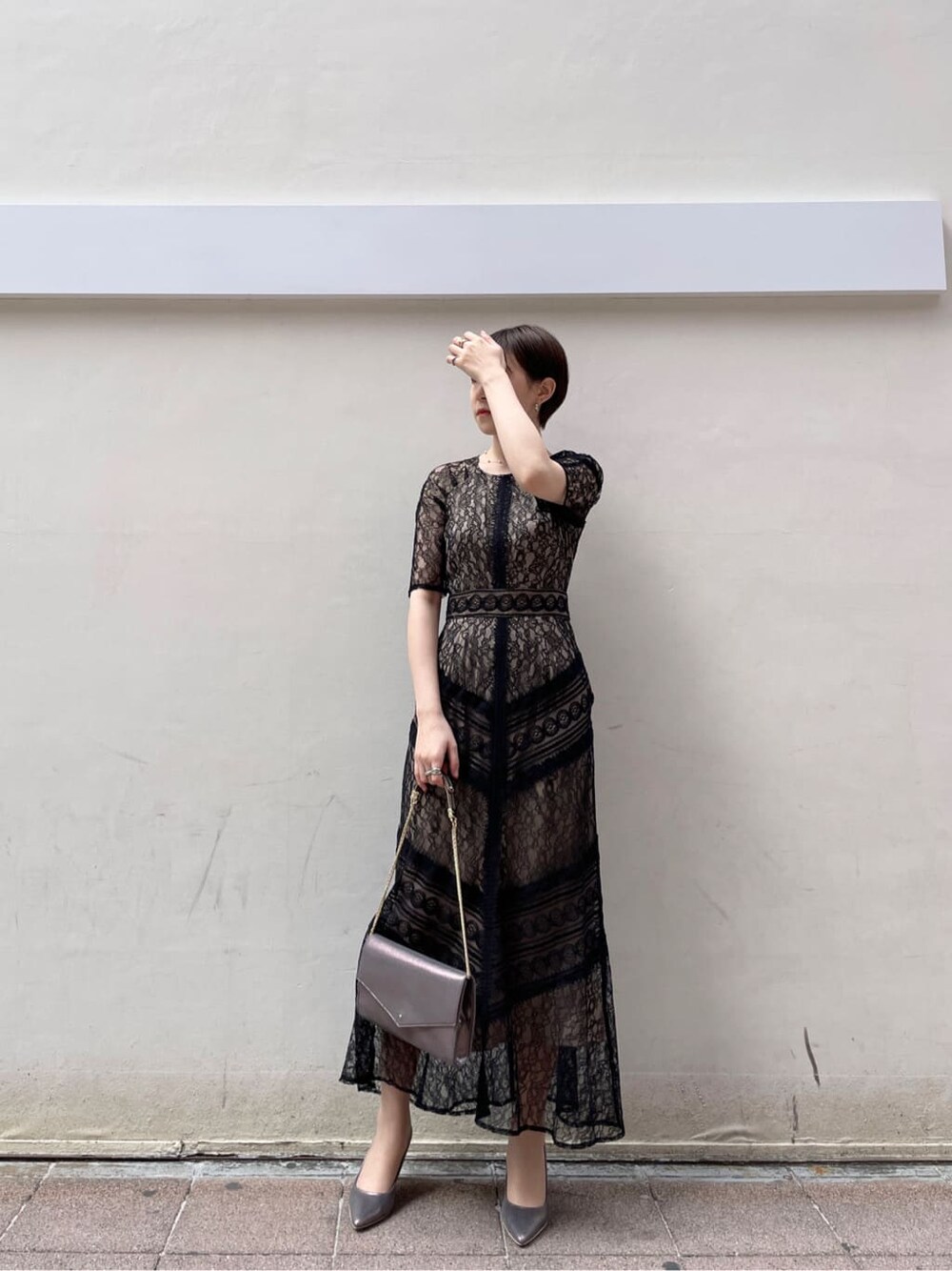 シルバー系のクラッチバッグ、ベージュ系のトレンチコート、シルバー系のパンプスを着用したレディースの冬コーディネートの2枚目の写真