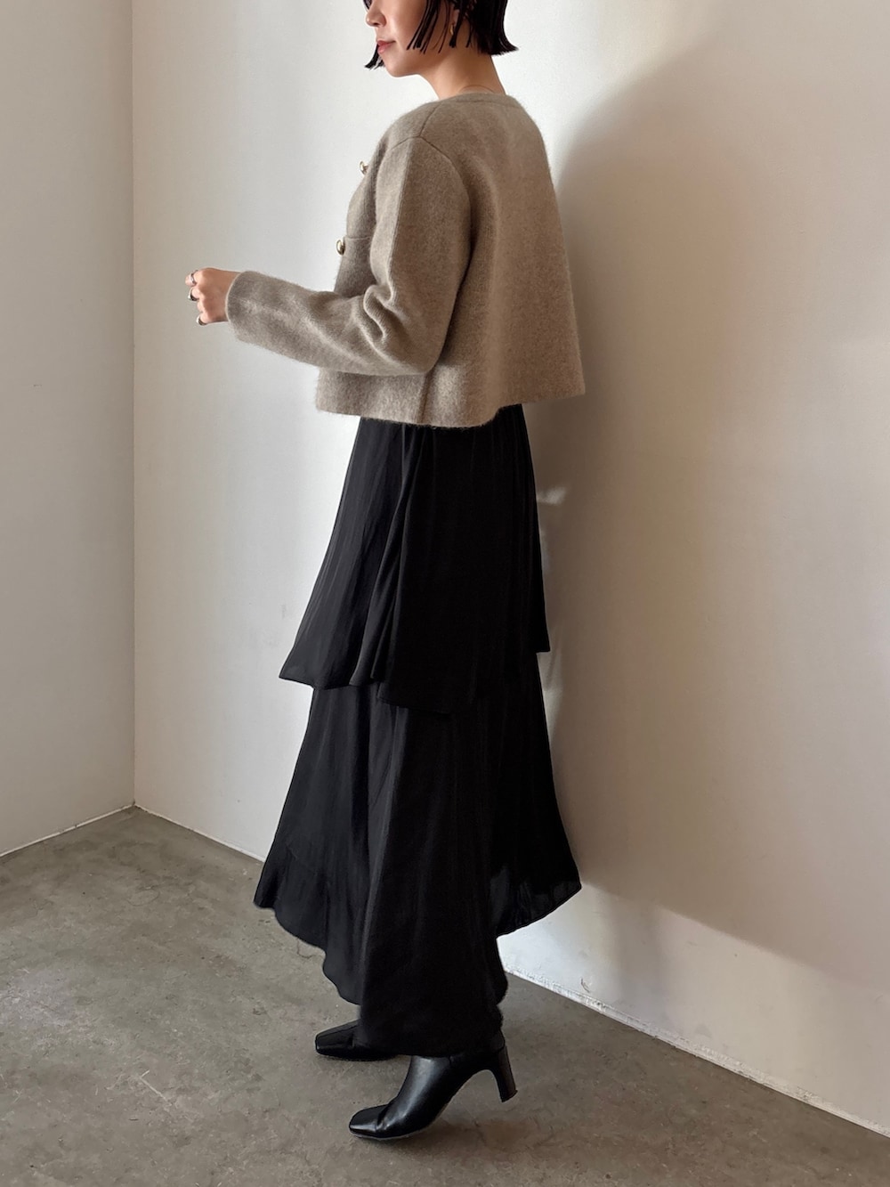 ブラック系のブーツ、ブラウン系のハンドバッグ、ブラック系のスカートを着用したレディースの秋コーディネートの4枚目の写真