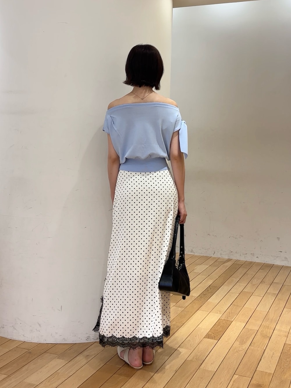 ブルー系のニット/セーター、ホワイト系のスカート、ブラック系のハンドバッグを着用したレディースの夏コーディネートの3枚目の写真