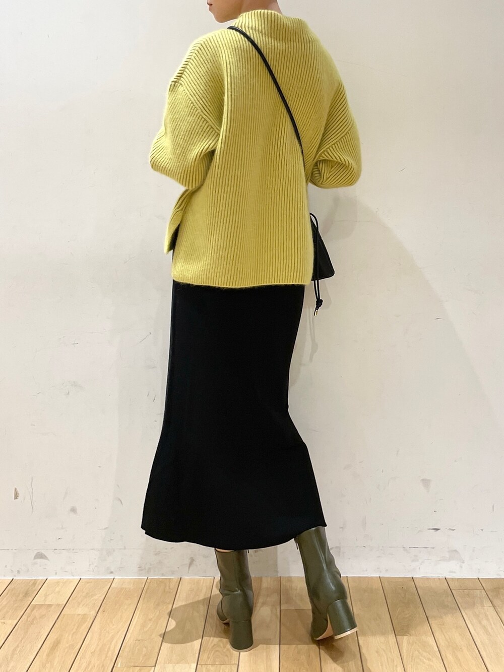 イエロー系のニット/セーター、ブラック系のスカート、ブラック系のハンドバッグを着用したレディースの冬コーディネートの3枚目の写真