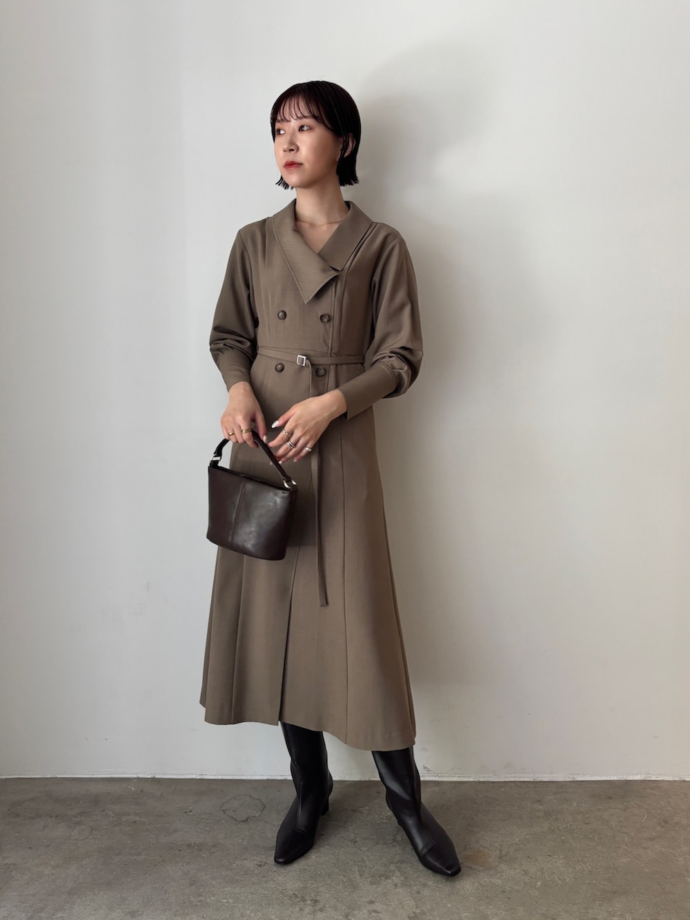 ホワイト系のワンピース、ブラウン系のハンドバッグ、ブラウン系のブーツを着用したレディースの秋コーディネートの2枚目の写真