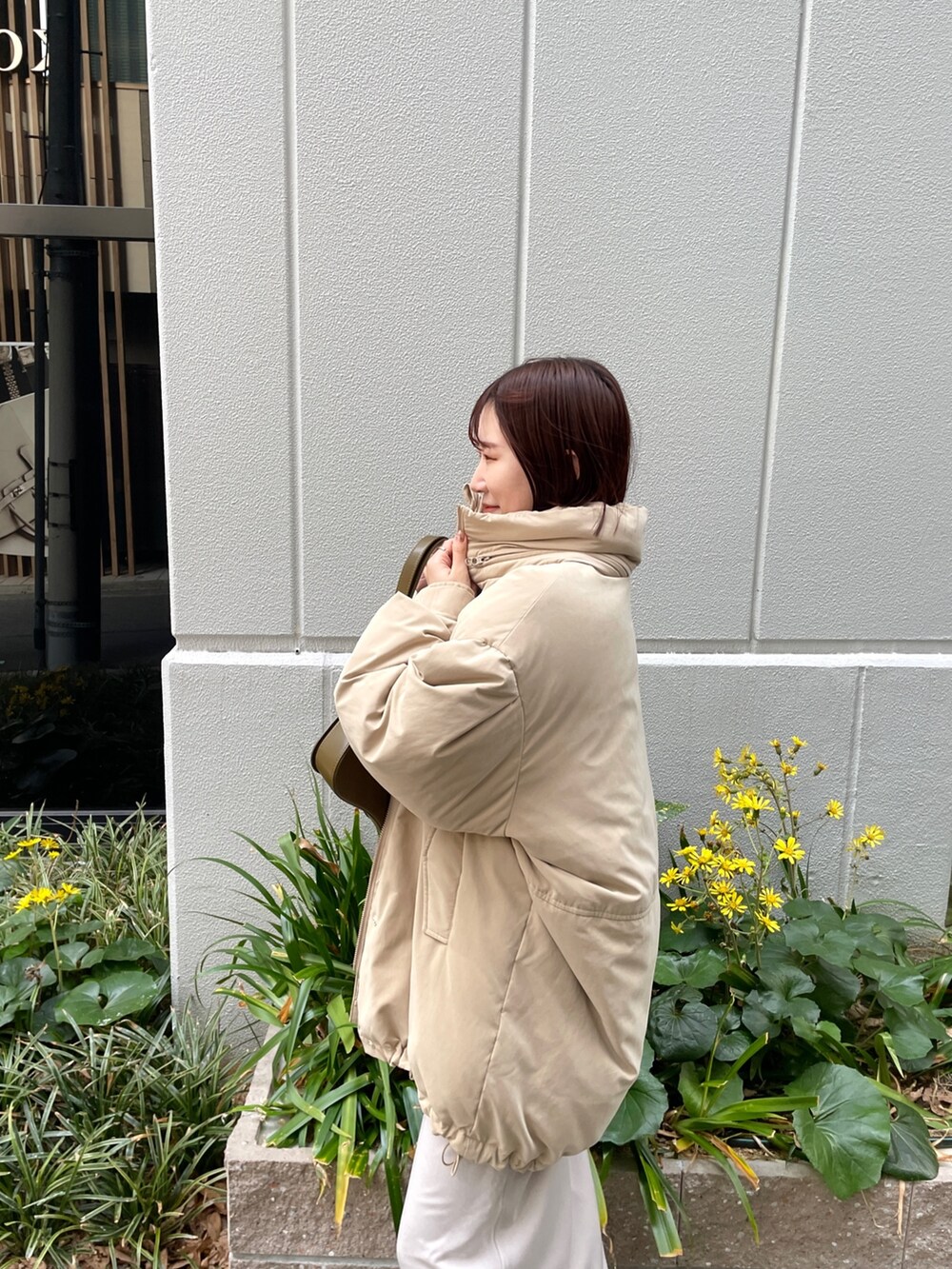 ベージュ系のダウンジャケット/コート、ホワイト系のスカート、ブラウン系のショルダーバッグを着用したレディースの冬コーディネートの5枚目の写真