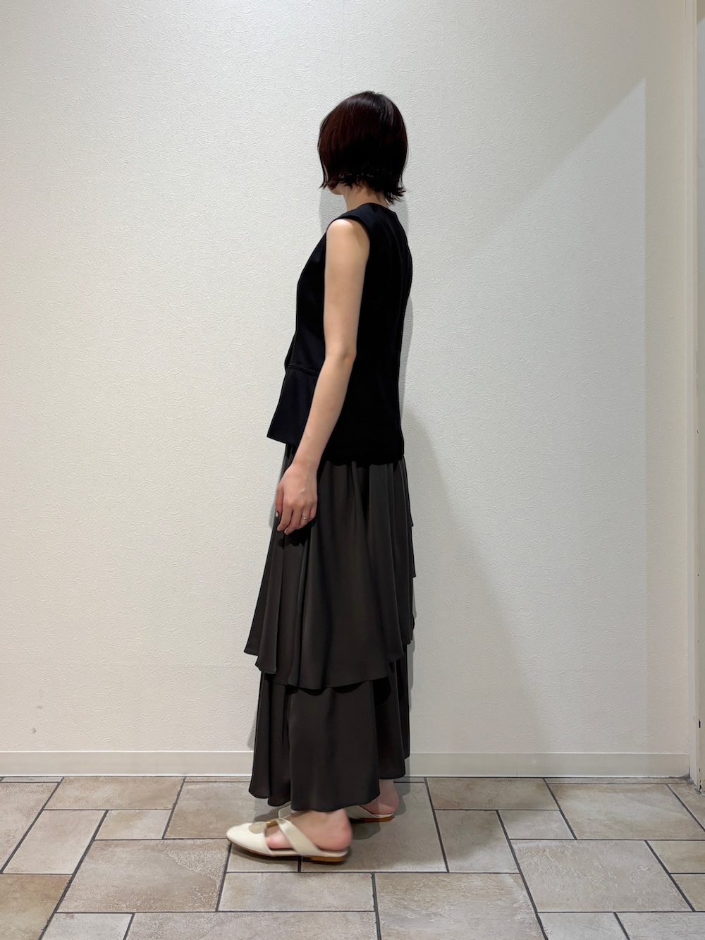 ブラック系のワンピース、ブラック系のハンドバッグ、ホワイト系のサンダルを着用したレディースの夏コーディネートの2枚目の写真