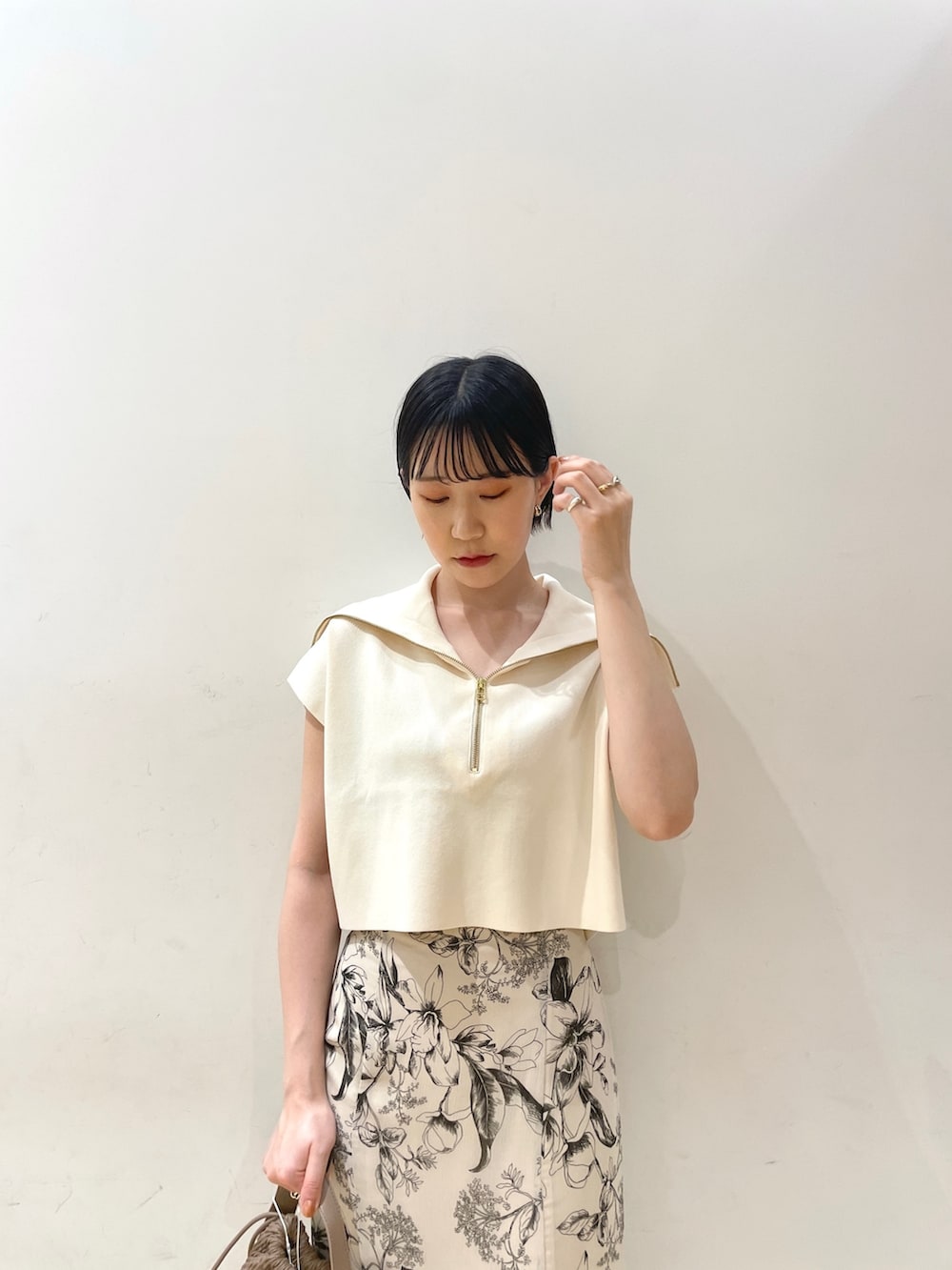 ホワイト系のニット/セーター、ホワイト系のスカート、ブラウン系のハンドバッグを着用したレディースの春コーディネートの5枚目の写真