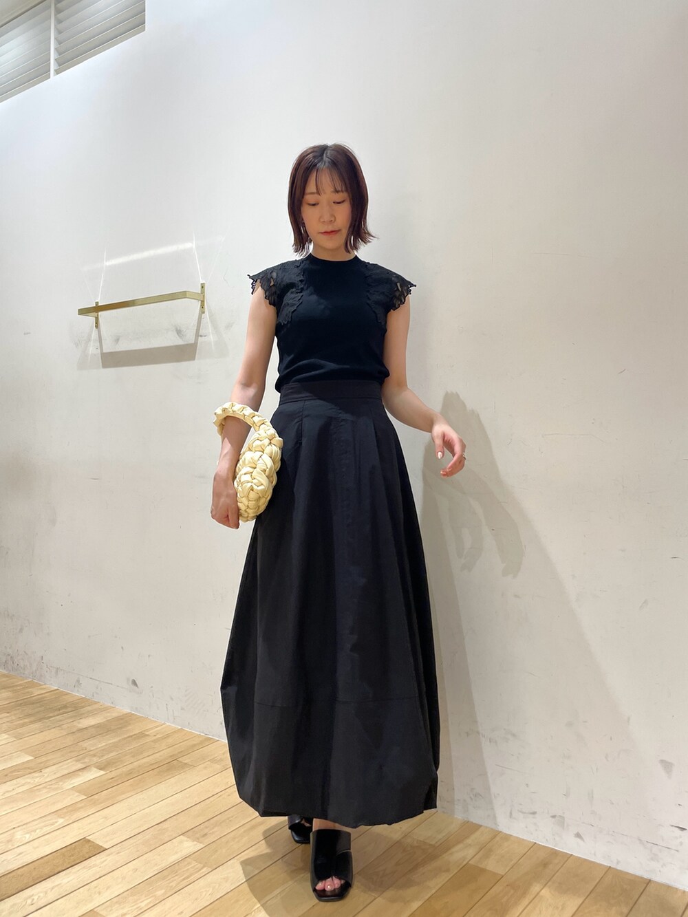 ベージュ系のハンドバッグ、ブラック系のサンダル、ブラック系のニット/セーターを着用したレディースの夏コーディネートの2枚目の写真