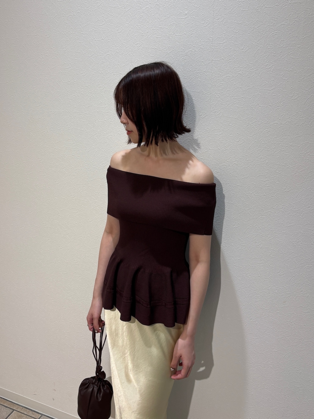 イエロー系のスカート、ブラウン系のハンドバッグ、ホワイト系のサンダルを着用したレディースの夏コーディネートの5枚目の写真
