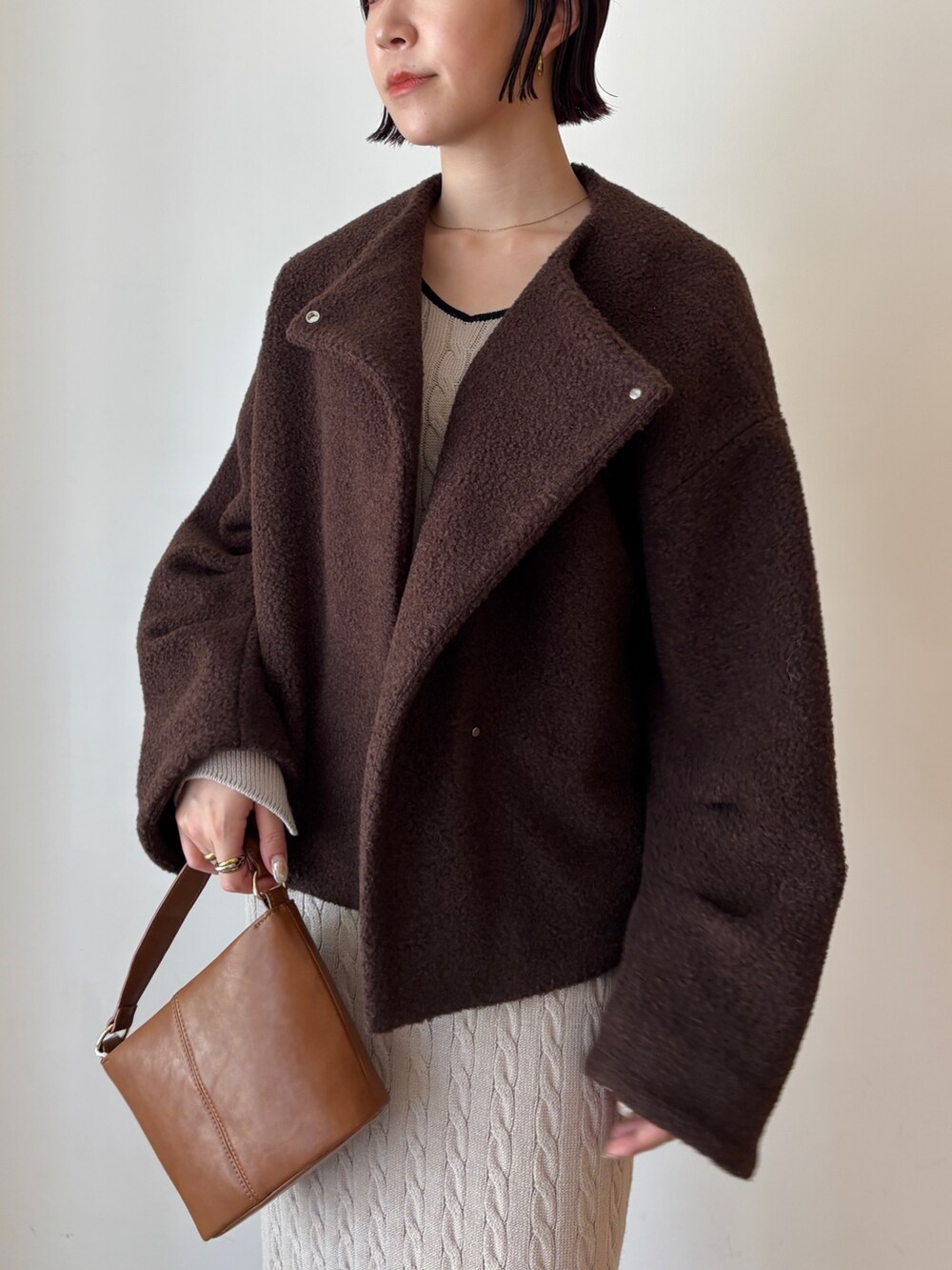 ベージュ系のワンピース、ブラウン系のブルゾン、ブラウン系のブーツを着用したレディースの秋コーディネートの7枚目の写真