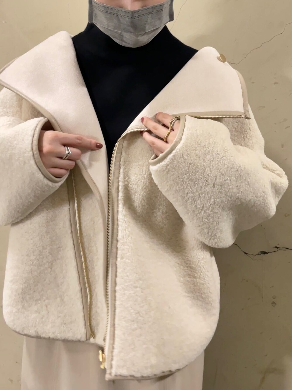 ホワイト系のブルゾン、ブラック系のブーツ、ベージュ系のスカートを着用したレディースの秋コーディネートの5枚目の写真