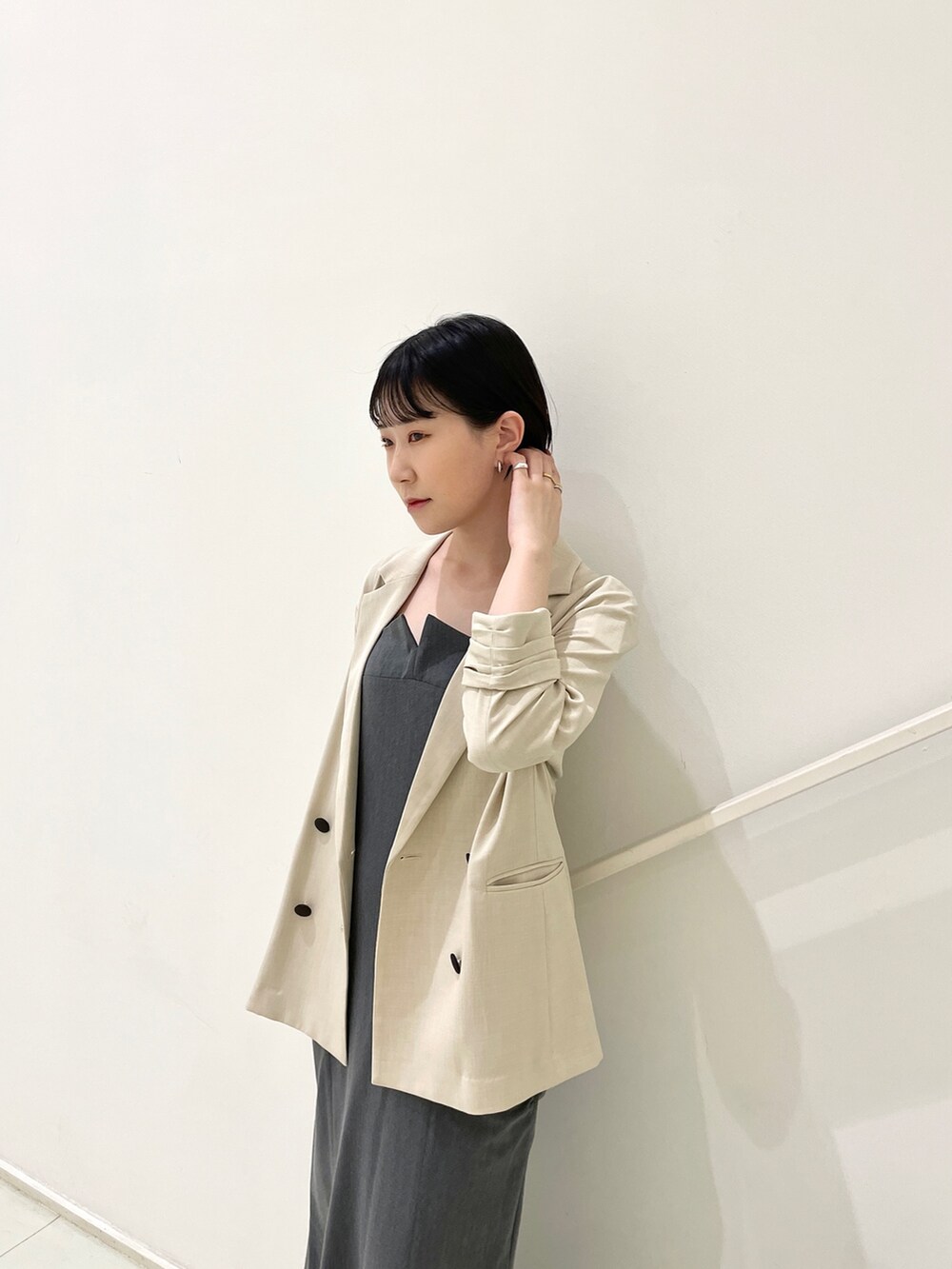 ベージュ系のテーラードジャケット、グレー系のワンピース、ブラック系のサンダルを着用したレディースの春コーディネートの5枚目の写真