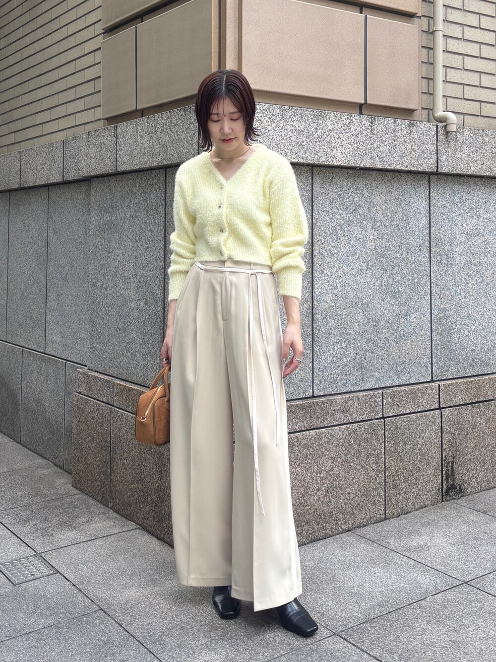 ベージュ系のその他パンツ、イエロー系のカーディガン/ボレロ、イエロー系のハンドバッグを着用したレディースの秋コーディネートの2枚目の写真