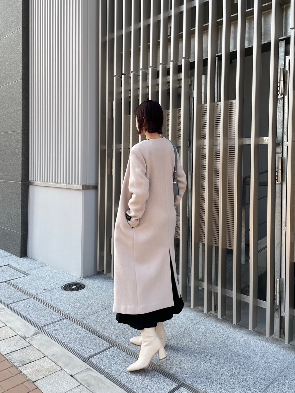 ブラック系のワンピース、ブルー系のショルダーバッグ、ホワイト系のブーツを着用したレディースの冬コーディネートの8枚目の写真