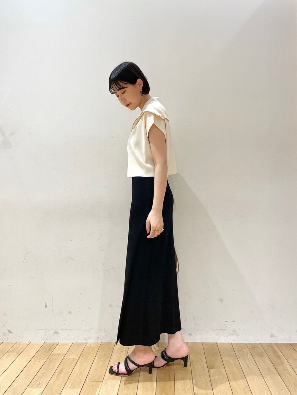 ブラック系のスカート、ホワイト系のニット/セーター、ブラウン系のハンドバッグを着用したレディースの春コーディネートの4枚目の写真