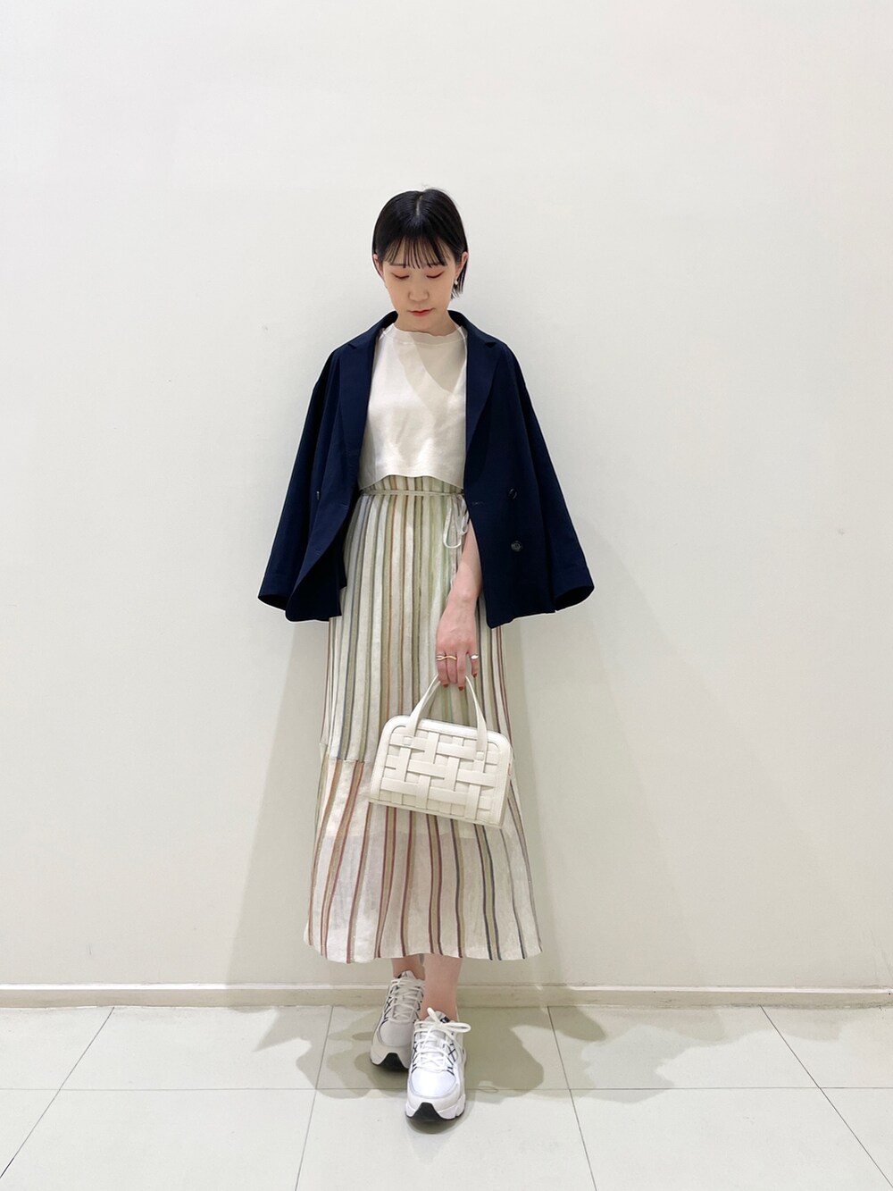 ブルー系のテーラードジャケット、ホワイト系のワンピース、ホワイト系のショルダーバッグを着用したレディースの春コーディネートの3枚目の写真