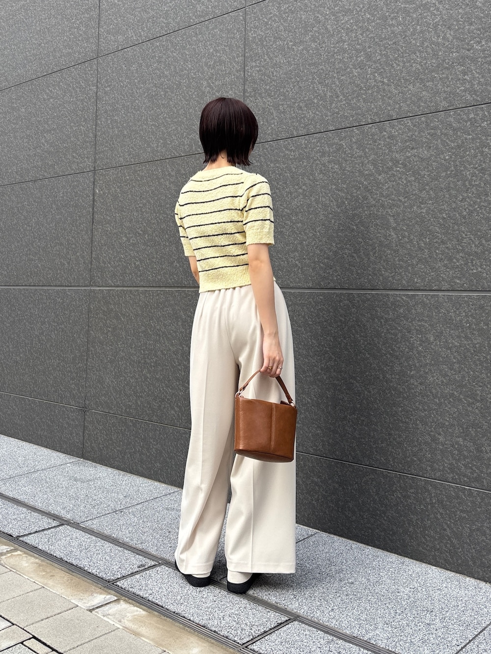 イエロー系のニット/セーター、ホワイト系のその他パンツ、イエロー系のハンドバッグを着用したレディースの春コーディネートの3枚目の写真