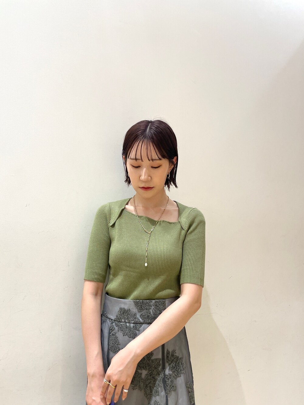 ベージュ系のブーツ、グリーン系のニット/セーター、グレー系のスカートを着用したレディースの夏コーディネートの7枚目の写真