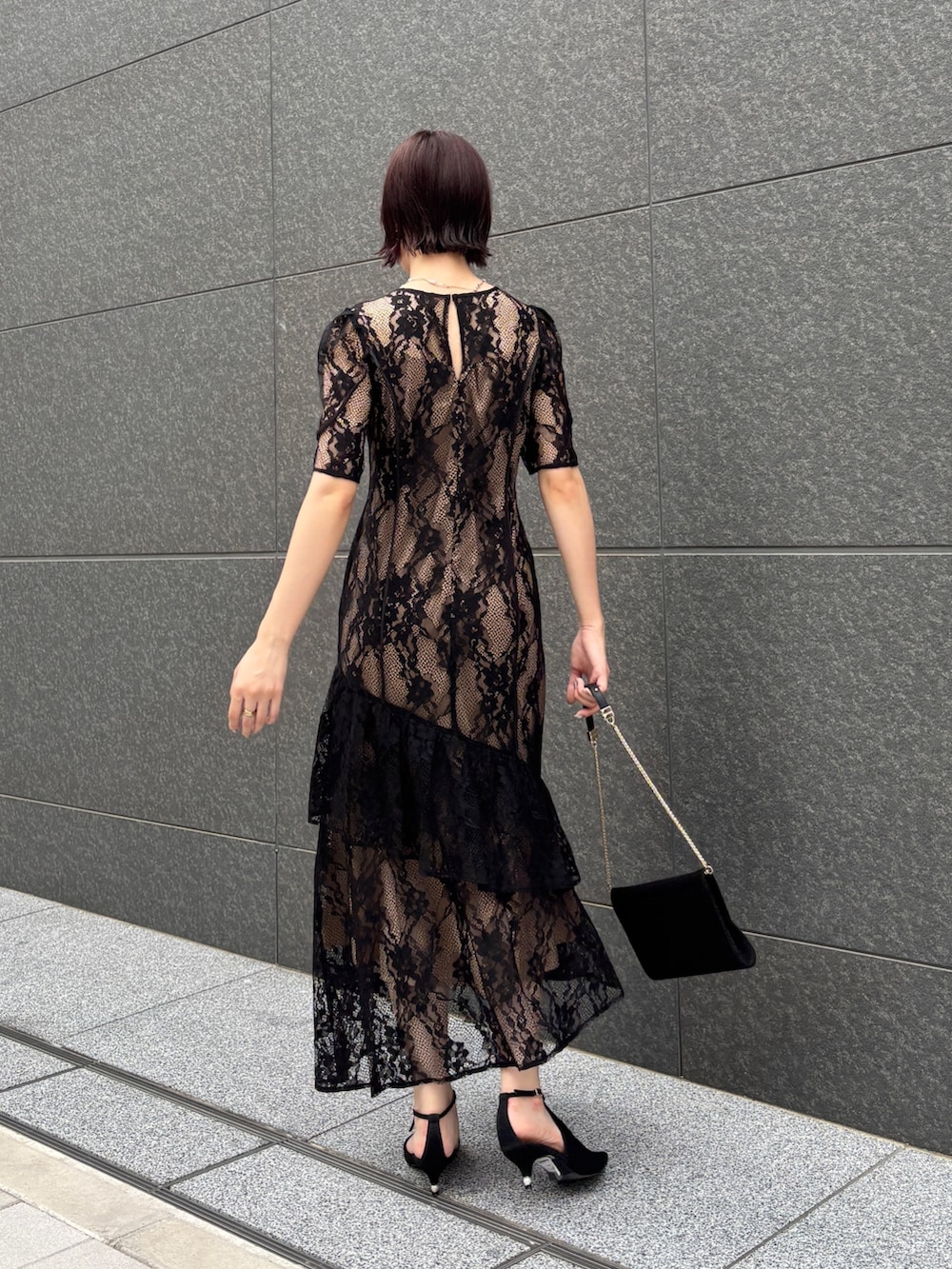 ブラック系のドレス、ブラック系のクラッチバッグ、ブラック系のパンプスを着用したレディースの秋コーディネートの4枚目の写真