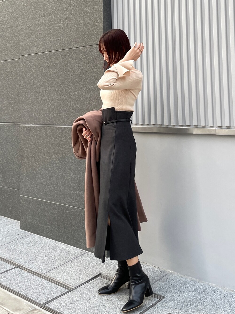 ブラウン系のチェスターコート、ホワイト系のニット/セーター、グレー系のスカートを着用したレディースの冬コーディネートの7枚目の写真