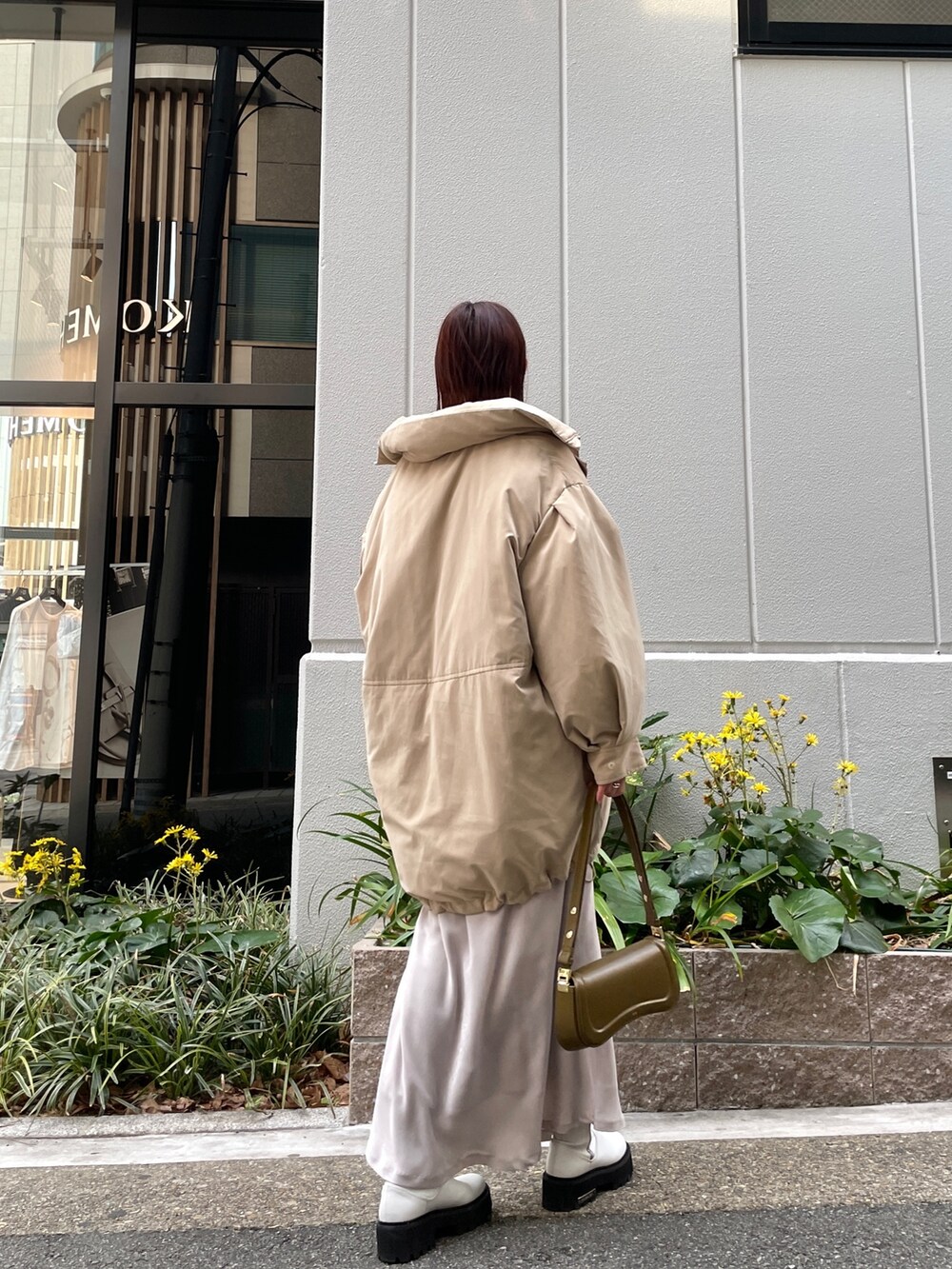 ベージュ系のダウンジャケット/コート、ホワイト系のスカート、ブラウン系のショルダーバッグを着用したレディースの冬コーディネートの3枚目の写真