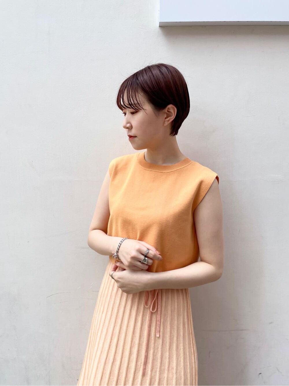 ホワイト系のテーラードジャケット、オレンジ系のワンピースを着用したレディースの春コーディネートの8枚目の写真