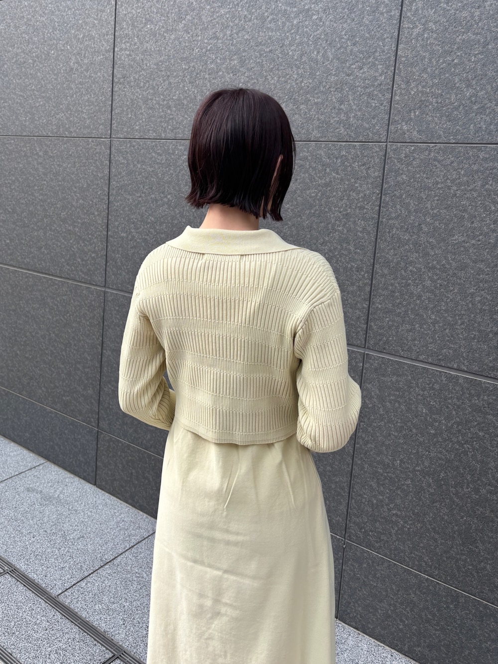 イエロー系のワンピース、ブラウン系のハンドバッグ、シルバー系のパンプスを着用したレディースの冬コーディネートの6枚目の写真