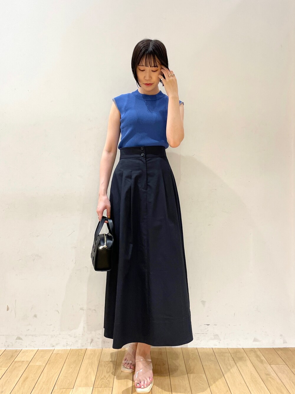 ブルー系のスカート、ブルー系のニット/セーター、ブラック系のショルダーバッグを着用したレディースの夏コーディネートの3枚目の写真