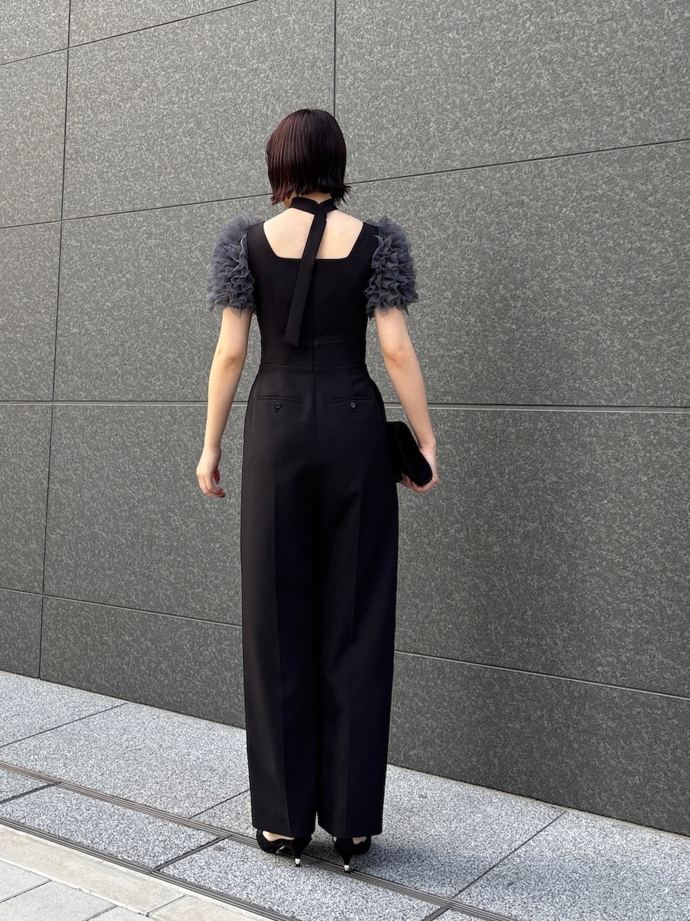 ブラック系のドレス、ブラック系のパンプス、ブラック系のハンドバッグを着用したレディースの冬コーディネートの3枚目の写真