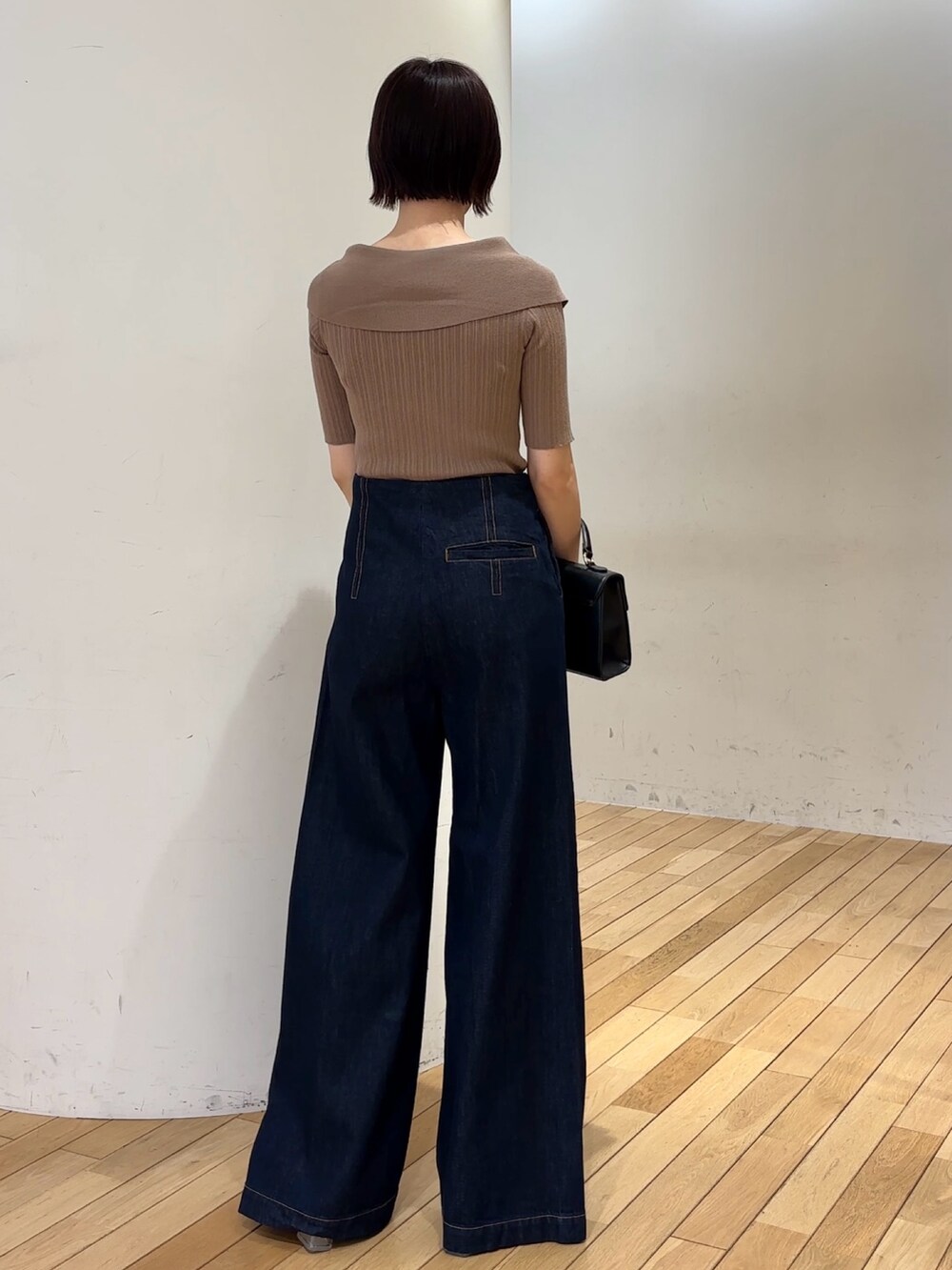 ブラック系のハンドバッグ、ブラック系のサンダル、ブルー系のデニムパンツを着用したレディースの春コーディネートの3枚目の写真