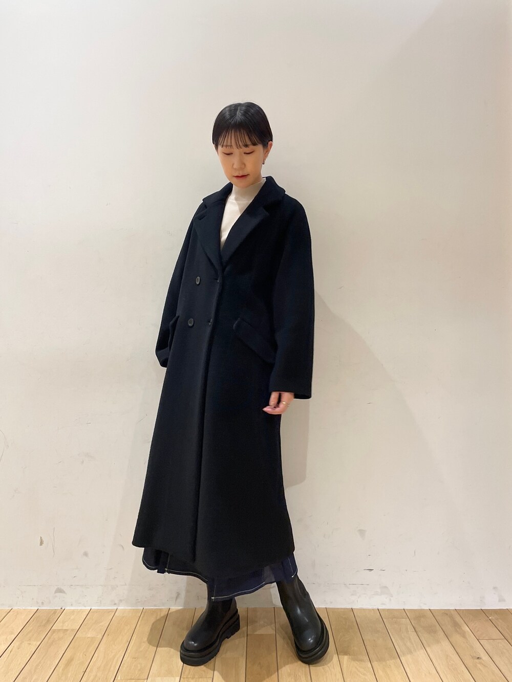 ブラック系のその他アウター、ホワイト系のニット/セーター、ブルー系のスカートを着用したレディースの冬コーディネートの6枚目の写真