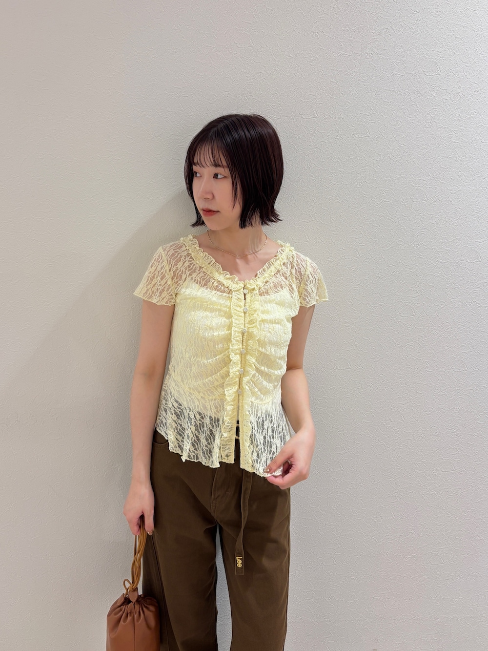 イエロー系のシャツ/ブラウス、ブラウン系のデニムパンツ、イエロー系のハンドバッグを着用したレディースの夏コーディネートの4枚目の写真