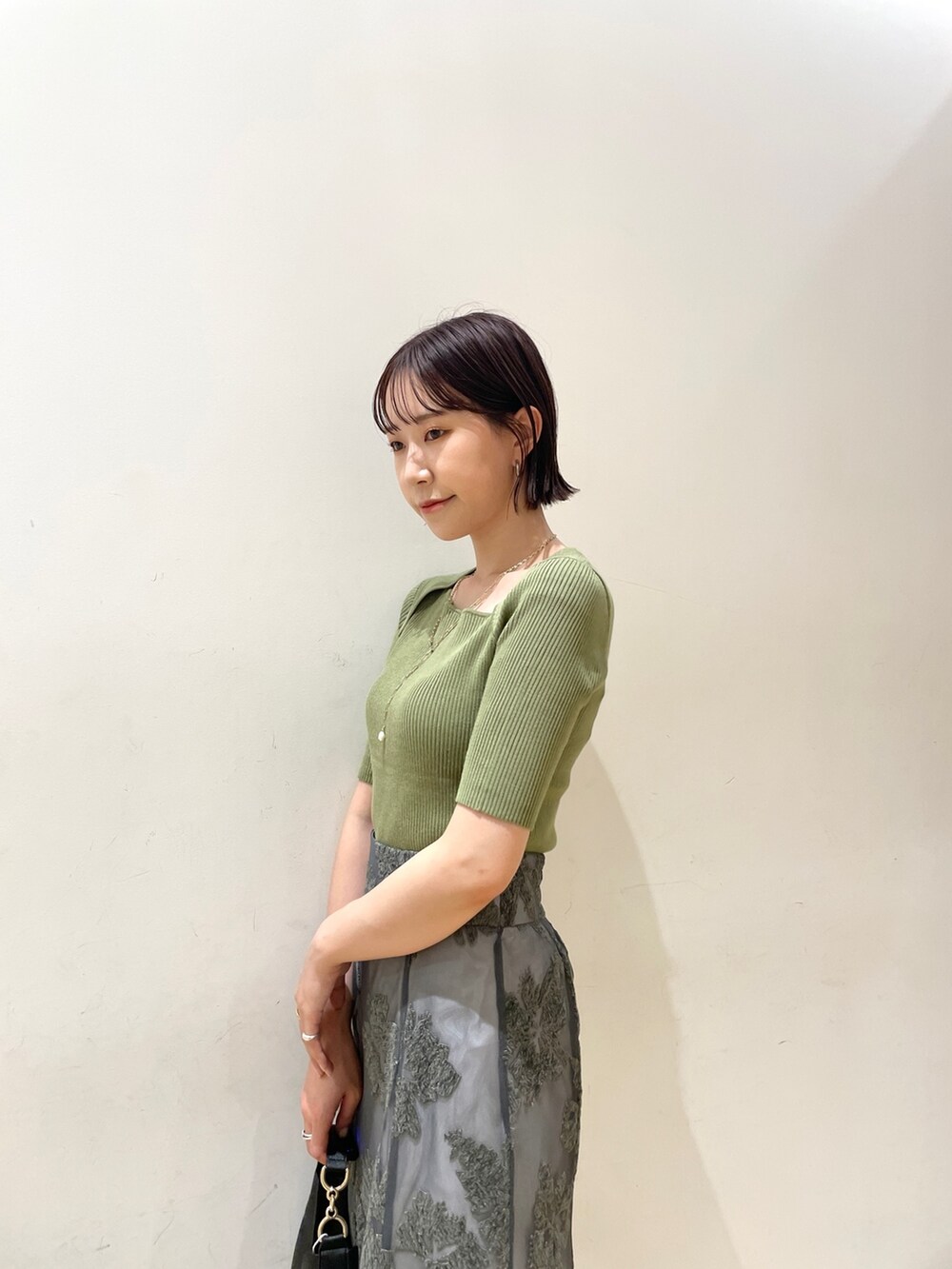 ベージュ系のブーツ、グリーン系のニット/セーター、グレー系のスカートを着用したレディースの夏コーディネートの8枚目の写真