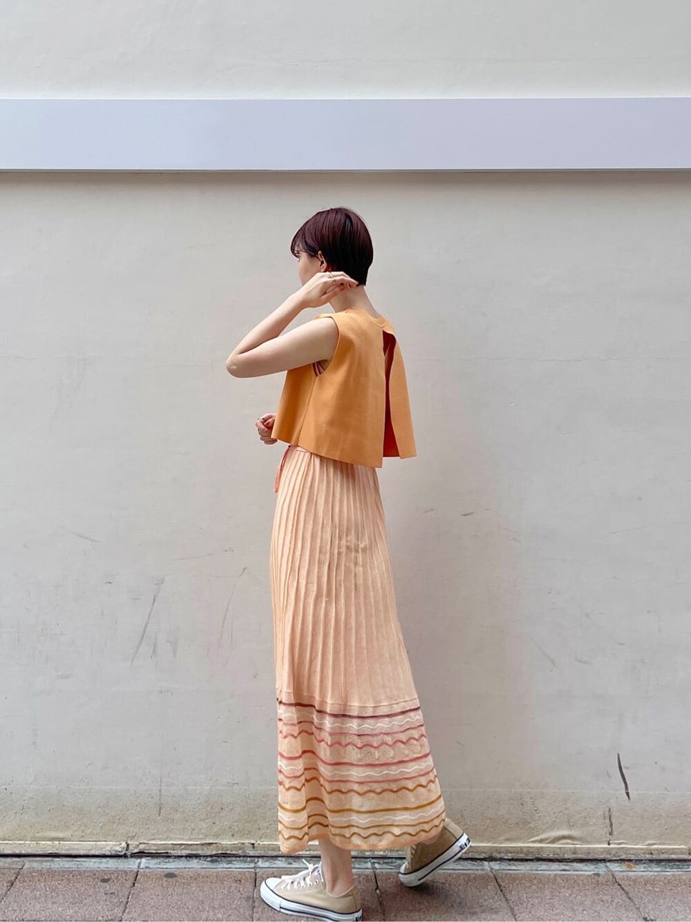 ホワイト系のテーラードジャケット、オレンジ系のワンピースを着用したレディースの春コーディネートの4枚目の写真