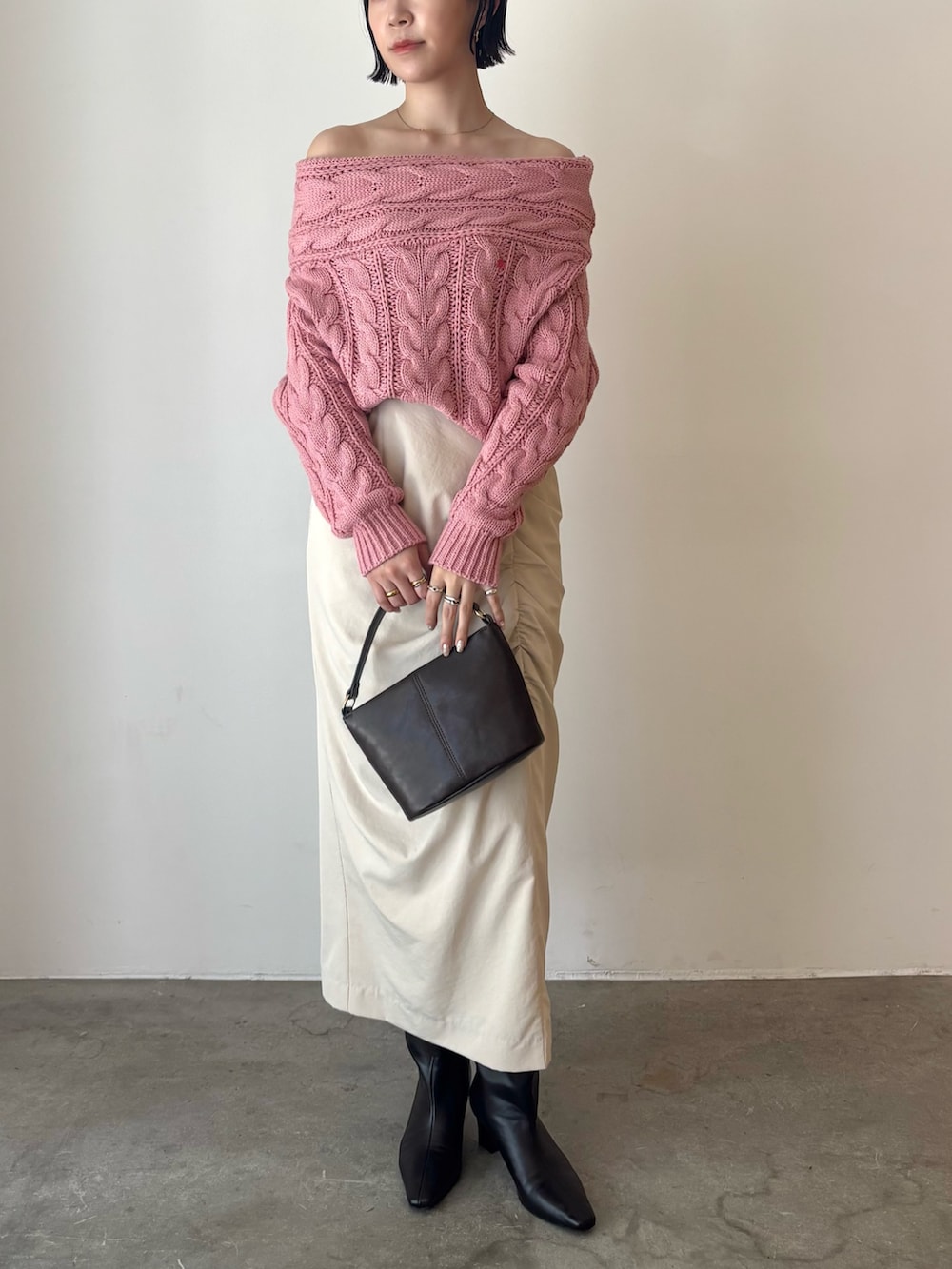 ピンク系のニット/セーター、ベージュ系のスカート、ブラウン系のハンドバッグを着用したレディースの秋コーディネートの2枚目の写真