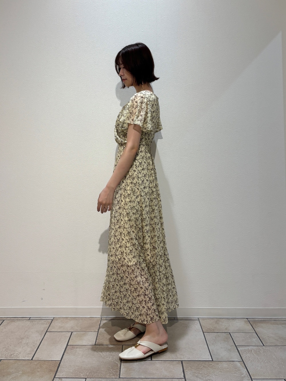 イエロー系のワンピース、ブラウン系のハンドバッグ、ホワイト系のサンダルを着用したレディースの夏コーディネートの3枚目の写真