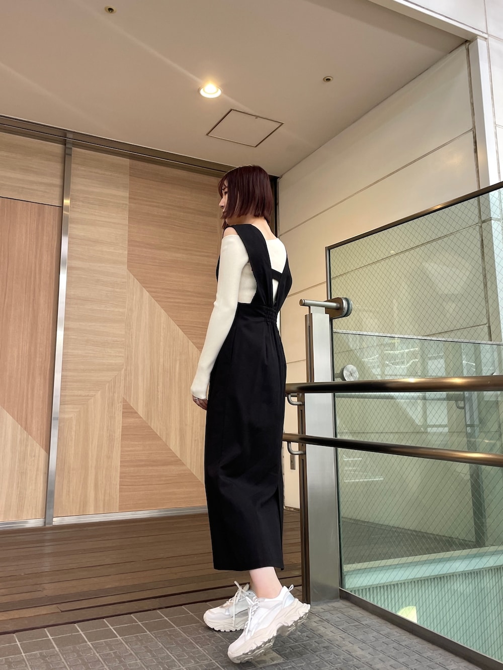 ブラック系のジャンパースカート、ホワイト系のショルダーバッグ、ホワイト系のニット/セーターを着用したレディースの春コーディネートの4枚目の写真