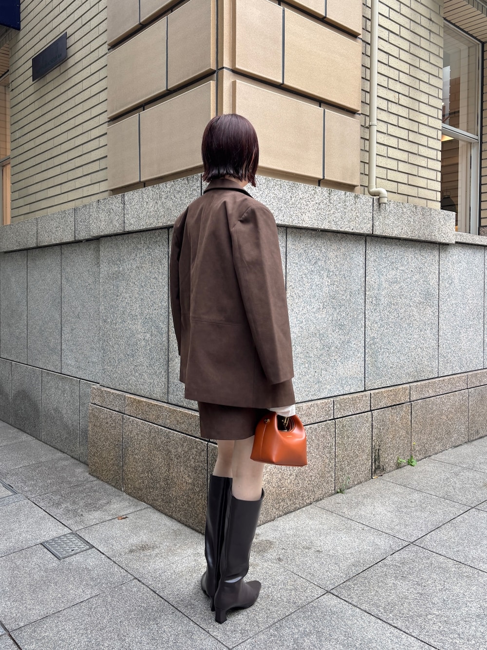 ブラウン系のブーツ、ブラウン系のハンドバッグ、ブラウン系のスカートを着用したレディースの秋コーディネートの6枚目の写真