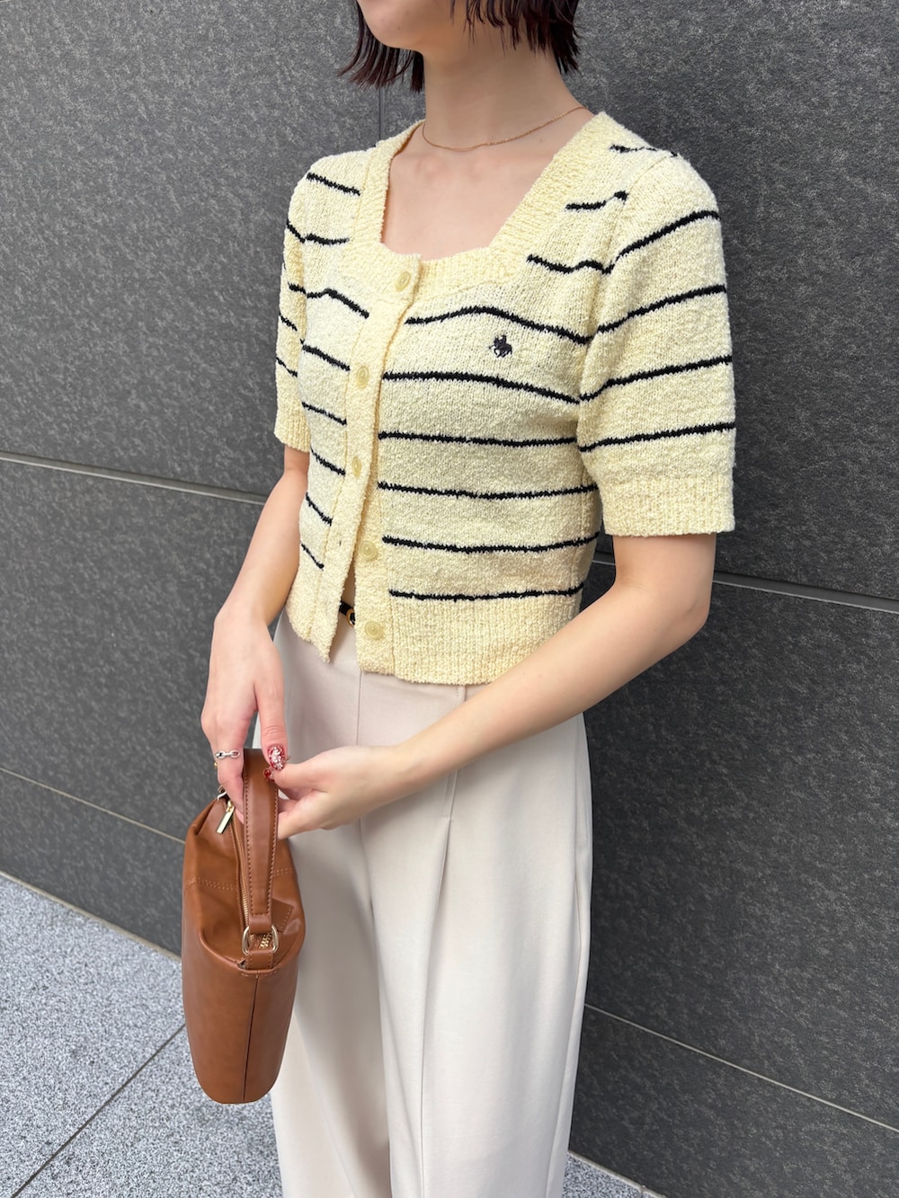 イエロー系のニット/セーター、ホワイト系のその他パンツ、イエロー系のハンドバッグを着用したレディースの春コーディネートの5枚目の写真