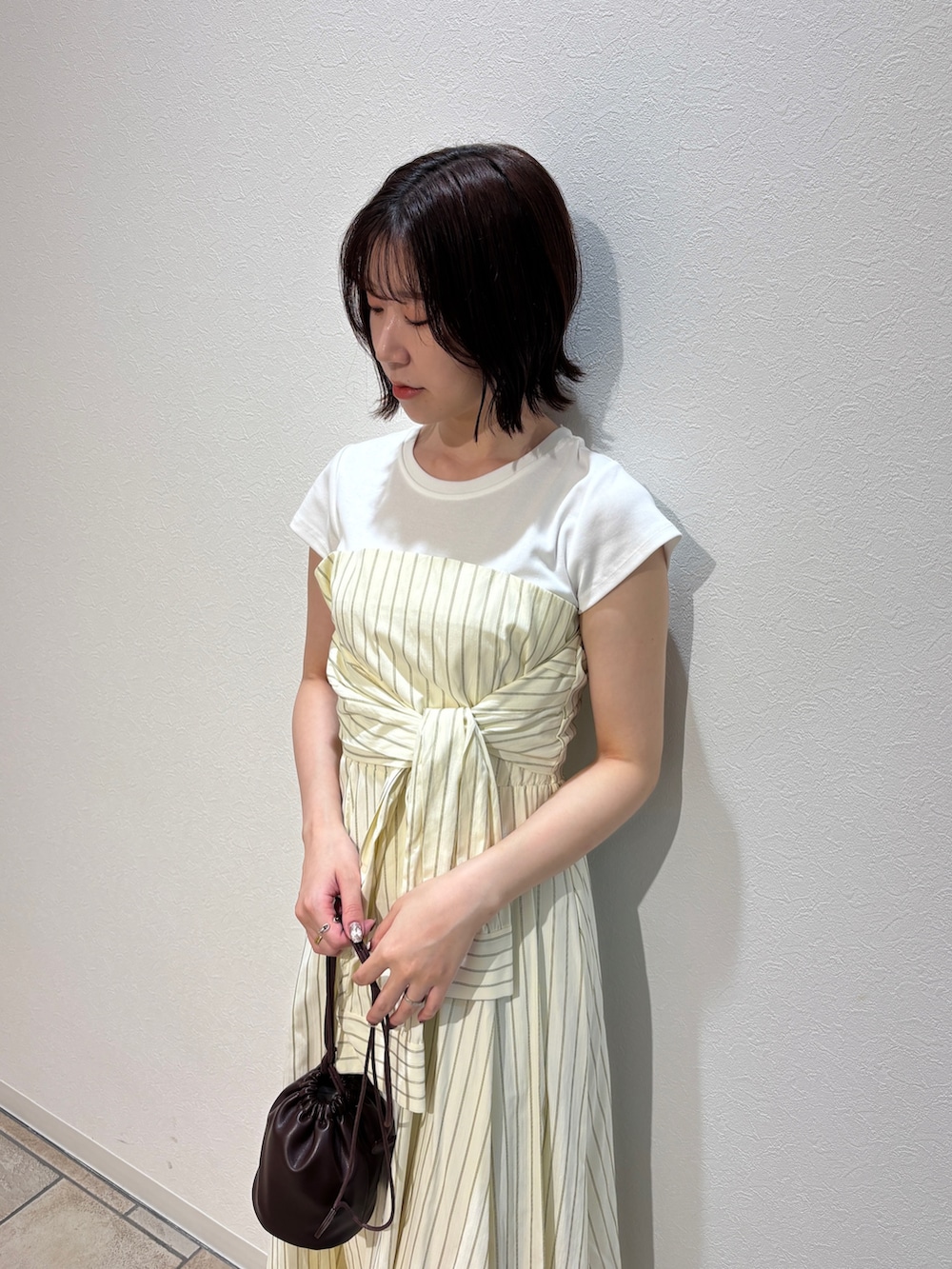 イエロー系のワンピース、ホワイト系のサンダル、ブラウン系のハンドバッグを着用したレディースの夏コーディネートの4枚目の写真
