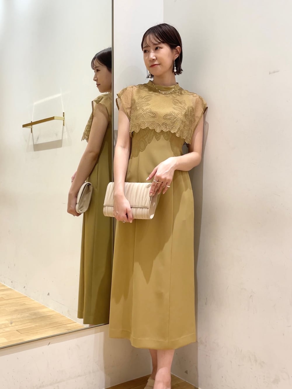 ベージュ系のドレス、ベージュ系のハンドバッグ、ベージュ系のパンプスを着用したレディースの秋コーディネートの3枚目の写真