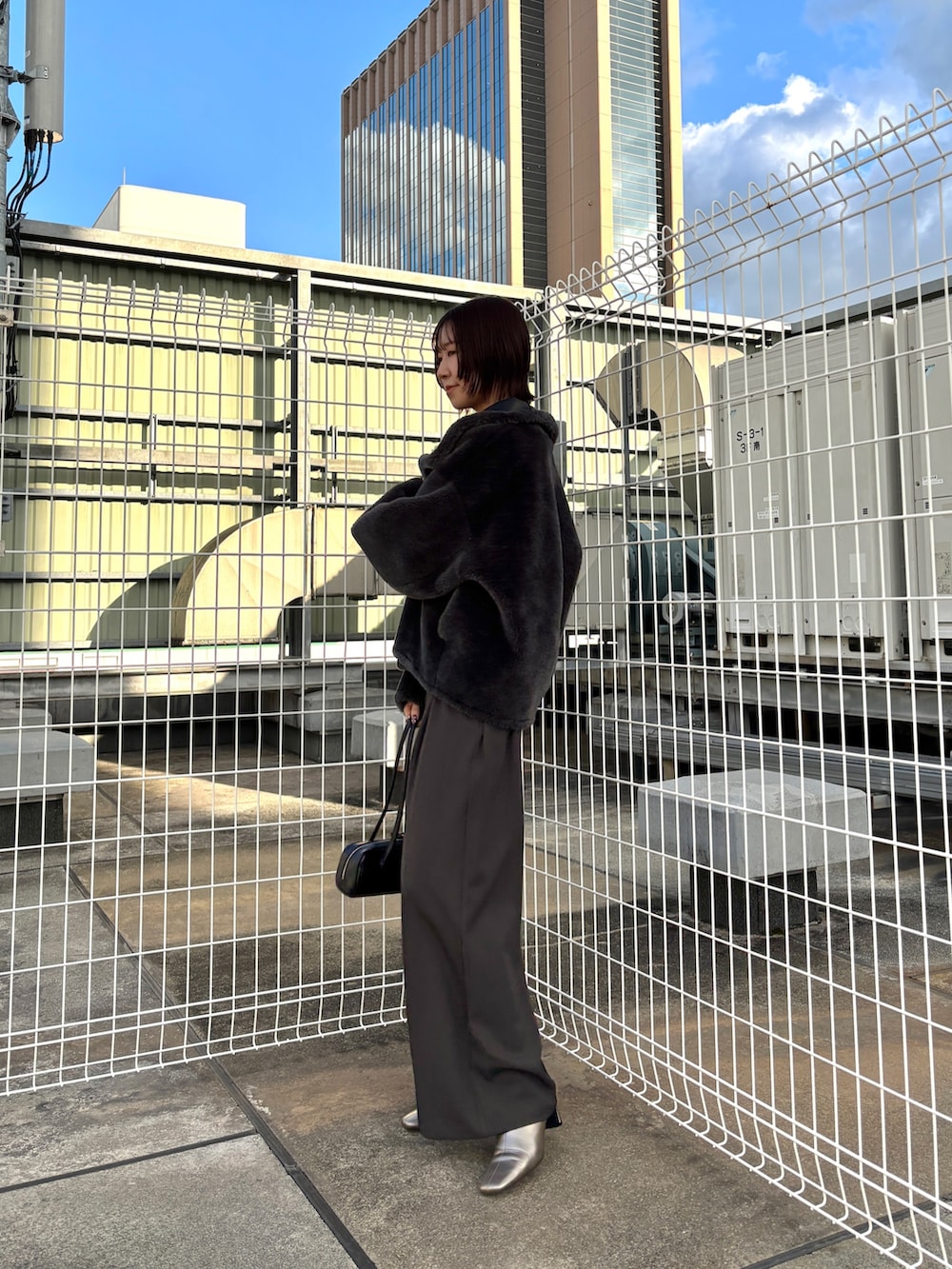 グレー系のその他パンツ、ブラック系のニット/セーター、グレー系のムートンコートを着用したレディースの冬コーディネートの6枚目の写真