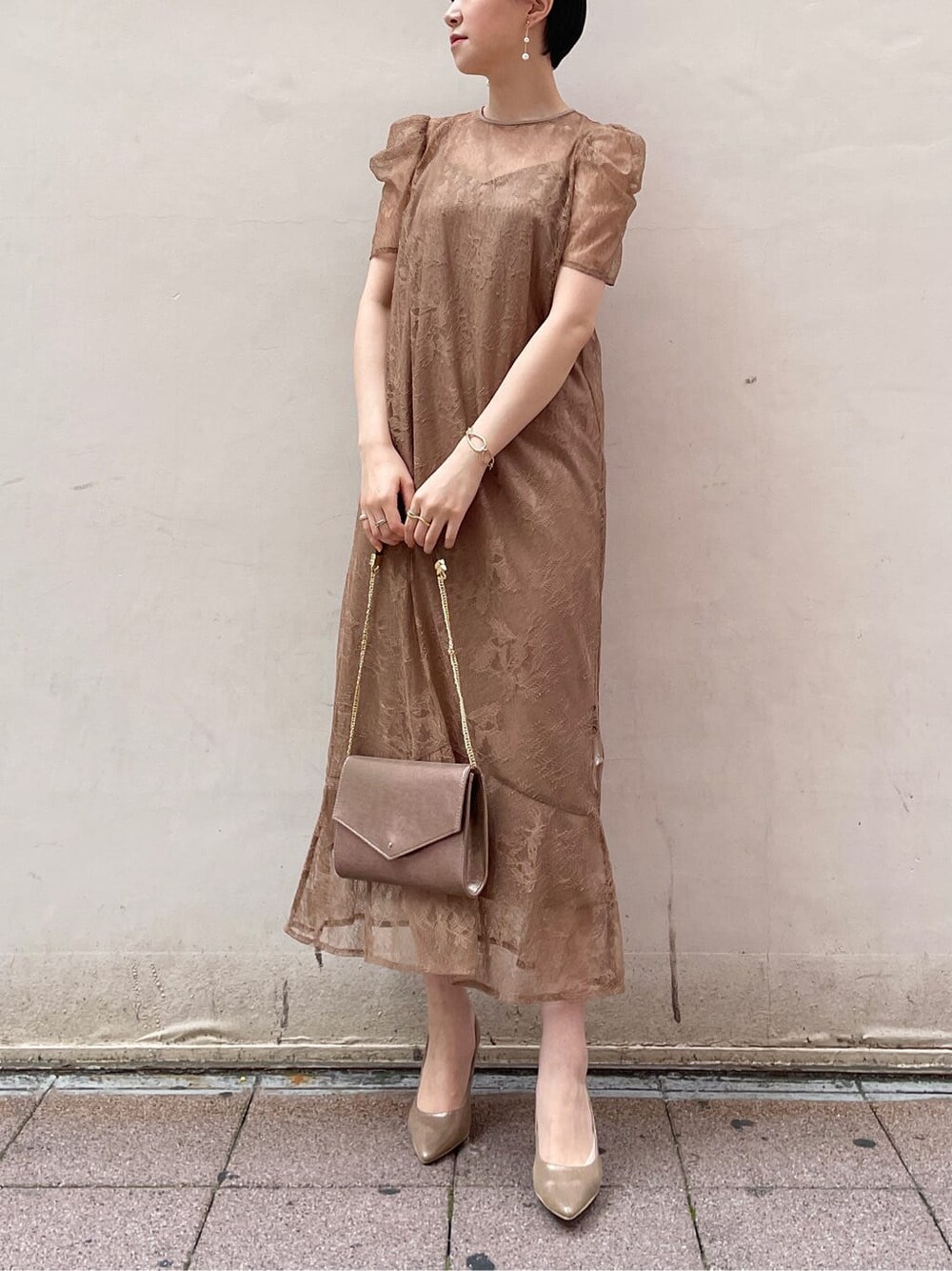 ゴールド系のパンプス、ゴールド系のクラッチバッグ、ベージュ系のドレスを着用したレディースの夏コーディネートの2枚目の写真