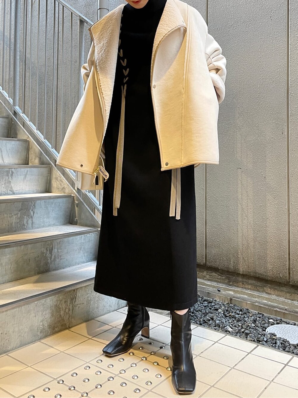 ブラック系のその他シューズ、ホワイト系のハンドバッグ、ブラック系のワンピースを着用したレディースの冬コーディネートの5枚目の写真